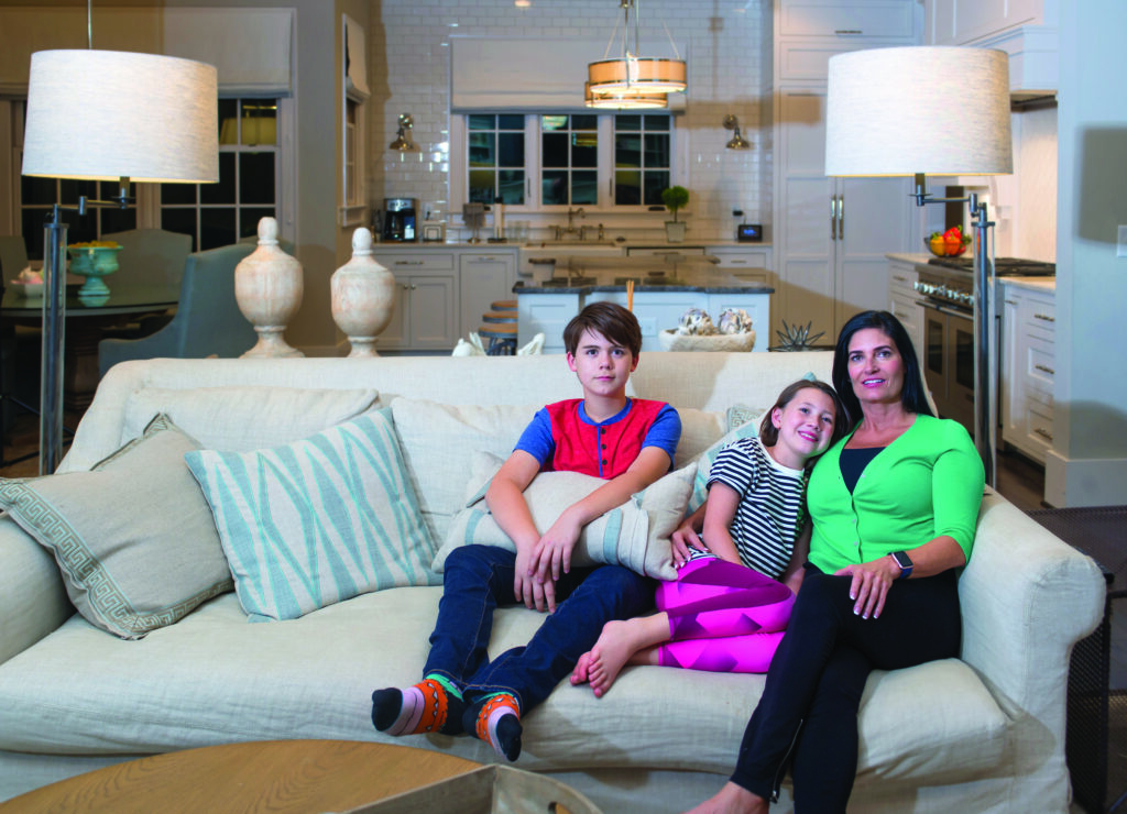 Mother, daughter, son sitting on living room couch watching TV at night. 